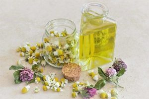 Chamomile essential oil with a jar full of chamomile petals