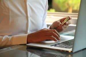 Photo of someone on a laptop with a credit card in his hand