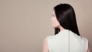 Picture of a woman from the back with shiny healthy hair looking to her left 