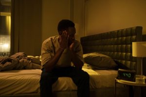 A man looking at his alarm clook showing late time indicating insomnia