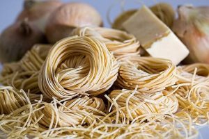 Dry pasta close up with out of focus onions and cheese