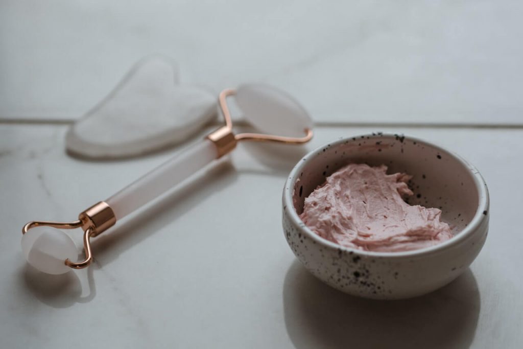 Rose face scrub next to skin care tools