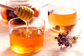 a bowl of honey next to dried flowers