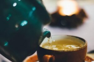 photograph of a teapot pouring tea into a teacup and background out of focus