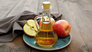 plate with apples and a bottle of apple cider vinegar 