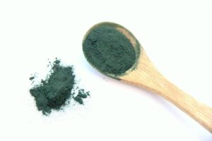 Spirulina powder in green color on a wooden spoon